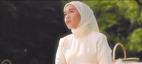 a woman wearing a white hijab and a white dress is looking up
