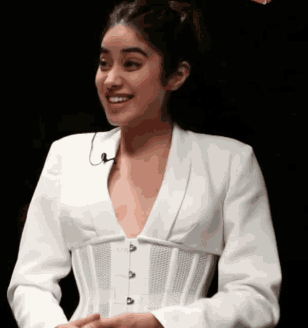 a woman wearing a white jacket and corset smiles