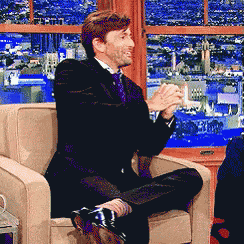 a man in a suit and tie is sitting in a chair with his legs crossed