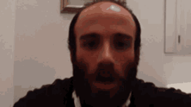 a man with a beard looks at the camera