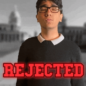 a man wearing glasses stands in front of a sign that says rejected in red letters