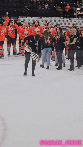 a hockey player holds a trophy in front of a crowd