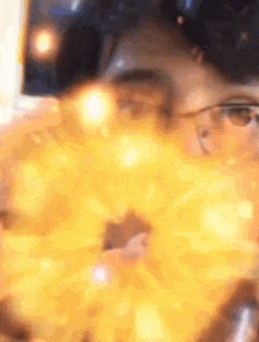 a blurry picture of a person wearing glasses and a yellow background