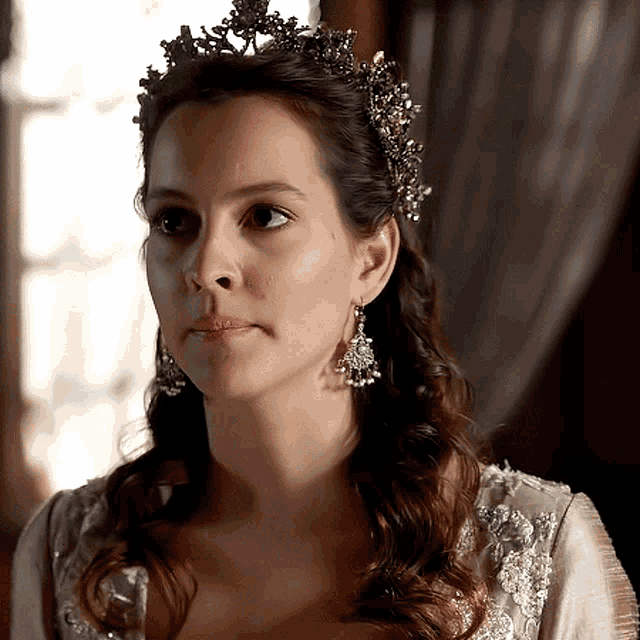 a woman is wearing a tiara and earrings