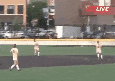 a group of people are playing a game of soccer on a field in front of a live sign .