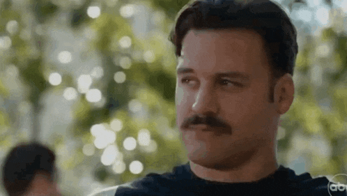 a close up of a man with a mustache looking at something .