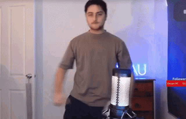 a man is dancing in front of a microphone in a room with a sign that says followers on it .