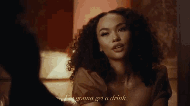 a woman with curly hair is talking to a man and says i 'm gonna get a drink