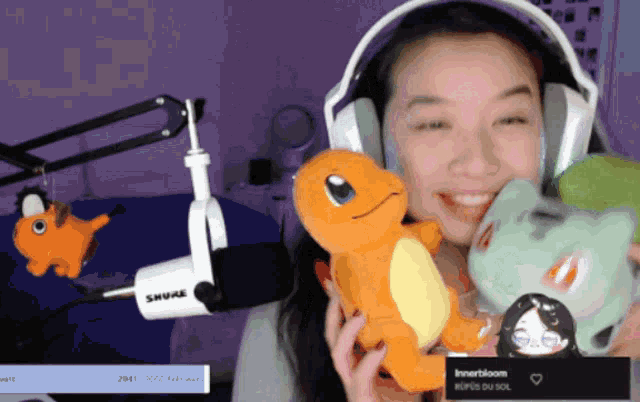 a woman wearing headphones holds a stuffed animal in front of a microphone that says shure