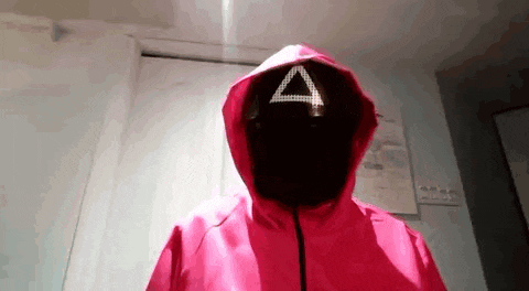 a person is wearing a squid game costume with a triangle mask .