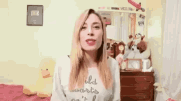 a woman is covering her mouth with her hand while wearing a sweatshirt that says let 's write it be