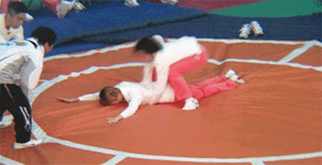 a group of children are wrestling on a mat in a gym