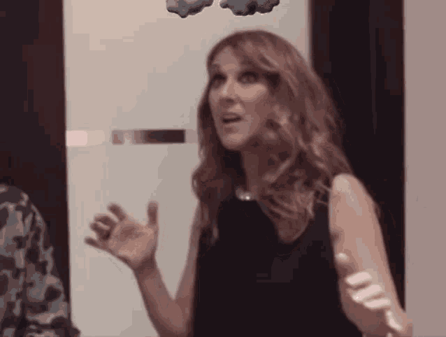 a woman in a black dress is standing in front of a door with two clouds flying in the air .