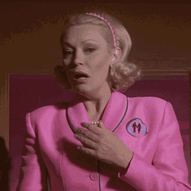 a woman in a pink suit has a button on her jacket that says ' mrs. ' on it