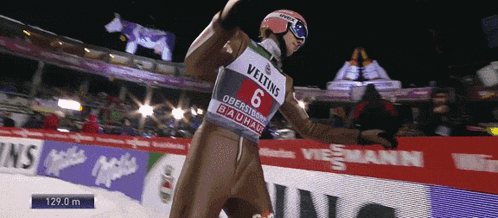 a skier wearing a veltins number 6 bib stands on the ice