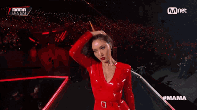 a woman in a red leather outfit is dancing on a stage with the word mama on the bottom