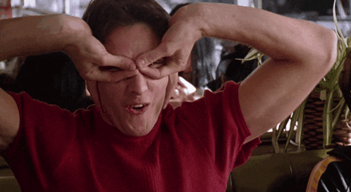a man wearing a red shirt is making a funny face with his hands
