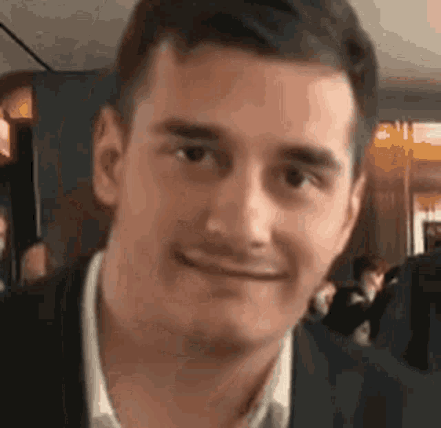 a man in a suit and tie is smiling for the camera .