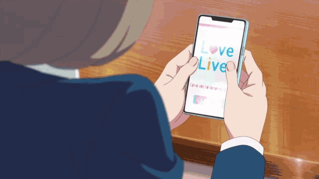a person holding a cell phone that says love live on the screen
