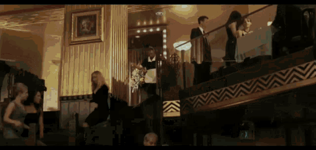 a group of people are gathered in a room with a chevron pattern on the stairs