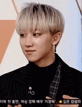 a close up of a young man wearing a black suit and earrings .