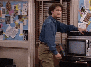 a man in a blue shirt is standing in front of a microwave