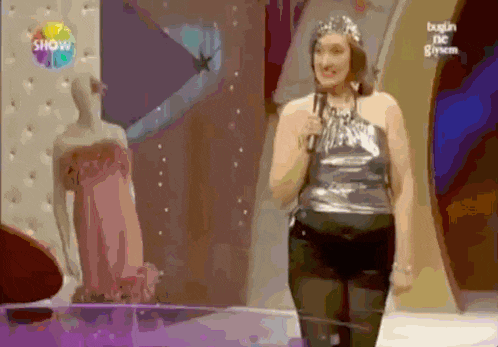 a woman singing into a microphone in front of a sign that says show on it