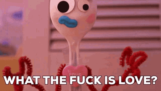 a toy fork with a heart and the words what the fuck is love behind it