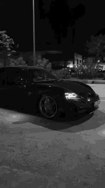 a car is driving down a street at night with a stop sign in the background .