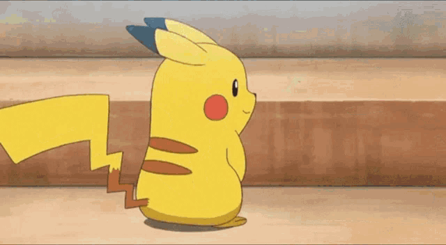 a cartoon pikachu is sitting on a wooden floor and looking at something .