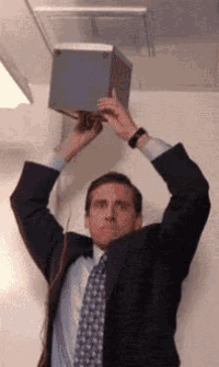 a man in a suit and tie is holding a box in his hands over his head .