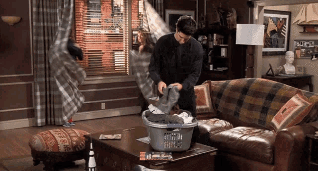 a man in a living room with a laundry basket