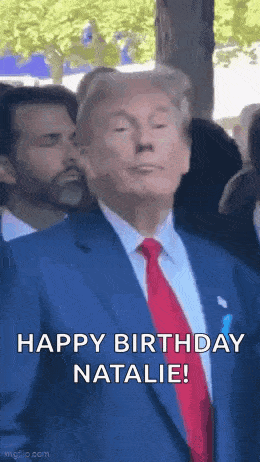a man in a suit and tie is standing in front of a crowd and says `` happy birthday natalie '' .