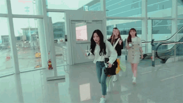 a group of girls are walking through an airport with a large window .
