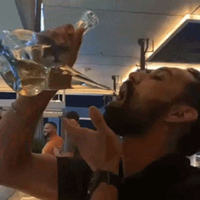 a man with a beard is drinking from a glass