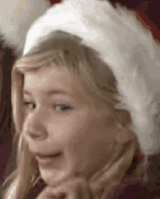 a little girl wearing a santa hat looks at the camera