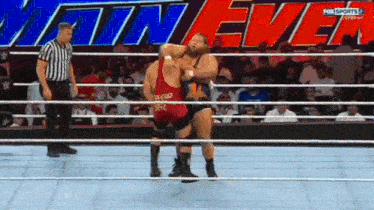 two men are wrestling in a ring with the words main event on the screen behind them