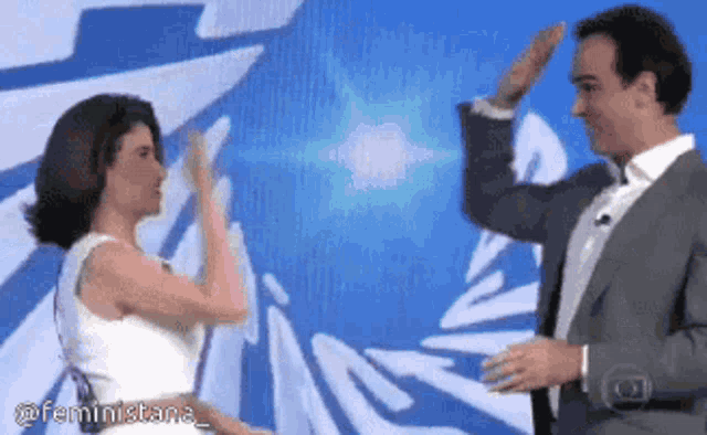 a man in a suit and a woman in a white dress are giving each other high fives