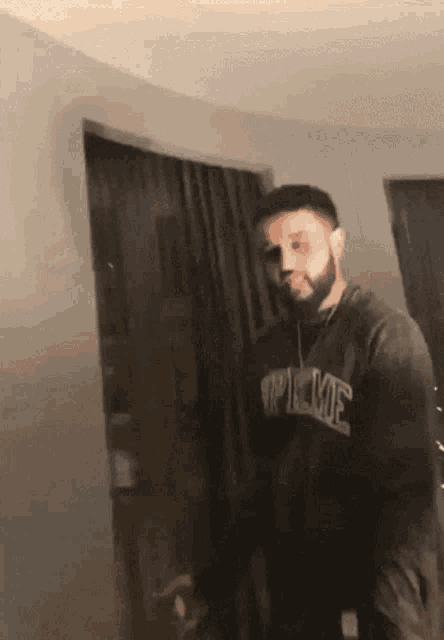 a man wearing a supreme sweatshirt stands in a room