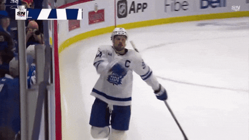 a hockey player wearing a maple leafs jersey is running on the ice