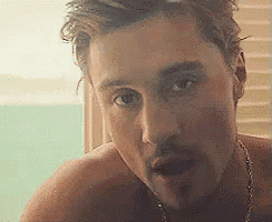 a shirtless man with a mustache is looking at the camera with his mouth open .