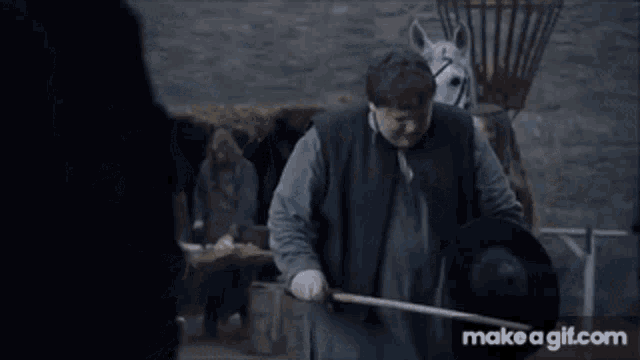 a man is standing next to a white horse while a woman looks on .