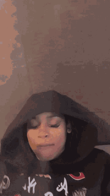 a woman wearing a black hoodie is making a face .