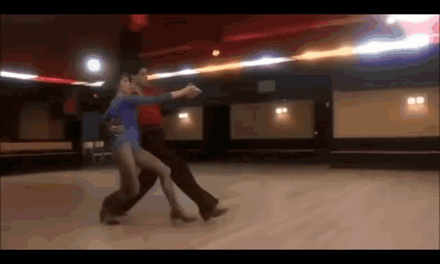 a man and a woman are dancing in an empty dance studio
