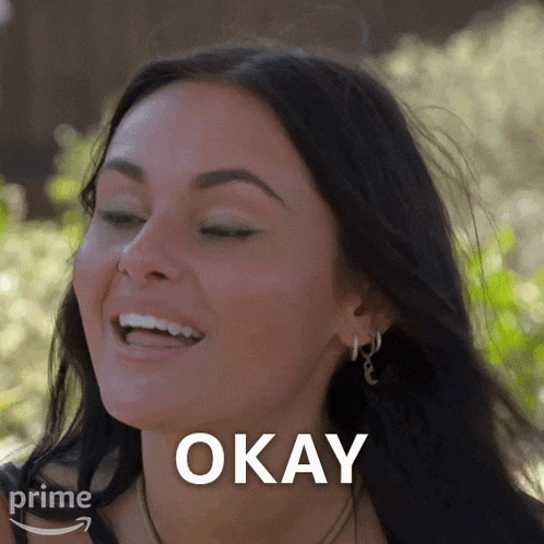 a woman is smiling and says okay in front of her face