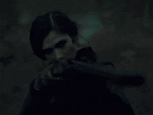 a woman holding a gun in her hand in the dark
