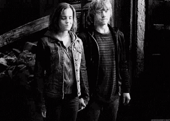 a black and white photo of a man and a woman standing next to each other in a dark room .