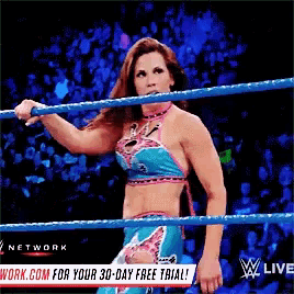 a woman is standing in a wrestling ring with a sign that says " w live "