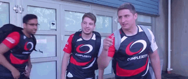 a group of men wearing complexity shirts are standing outside of a building