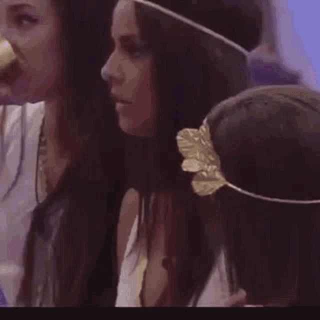 a group of women are standing next to each other in a room . one of the women is wearing a flower headband .